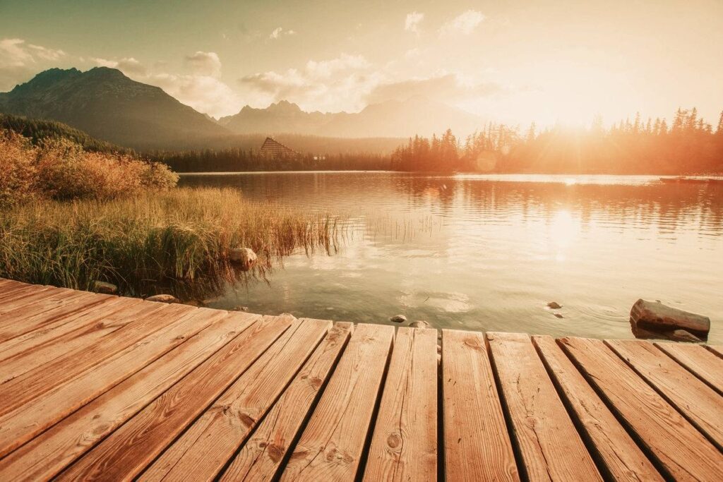 A wooden dock with water and mountains in the background.