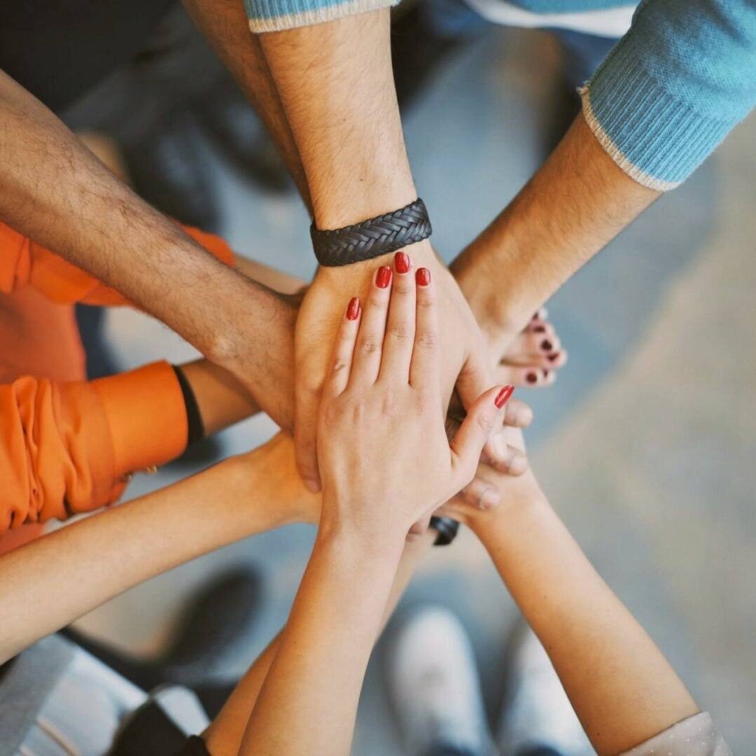 A group of people holding hands in the middle of a circle.
