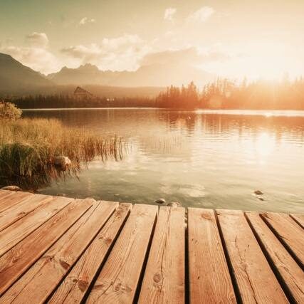 A wooden dock in front of a lake with mountains and trees.